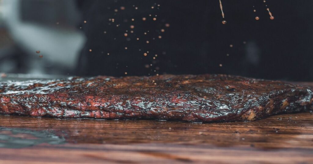 BBQ brisket meat being seasoned