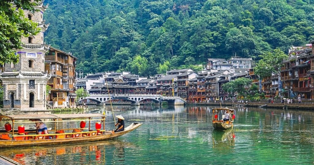 Forests, buildings, and river boats along the river in Fenguang Town in China