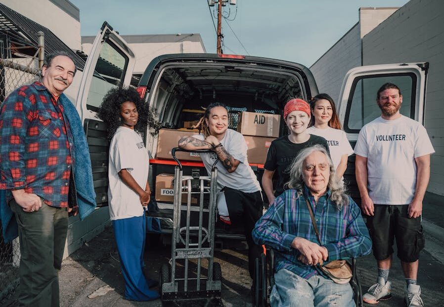 A diverse group of volunteers packing aid supplies into a van for donation.