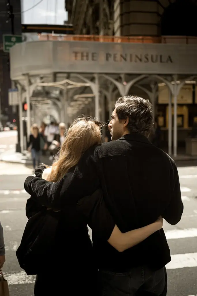A couple embraces lovingly at a crosswalk near The Peninsula in NYC.