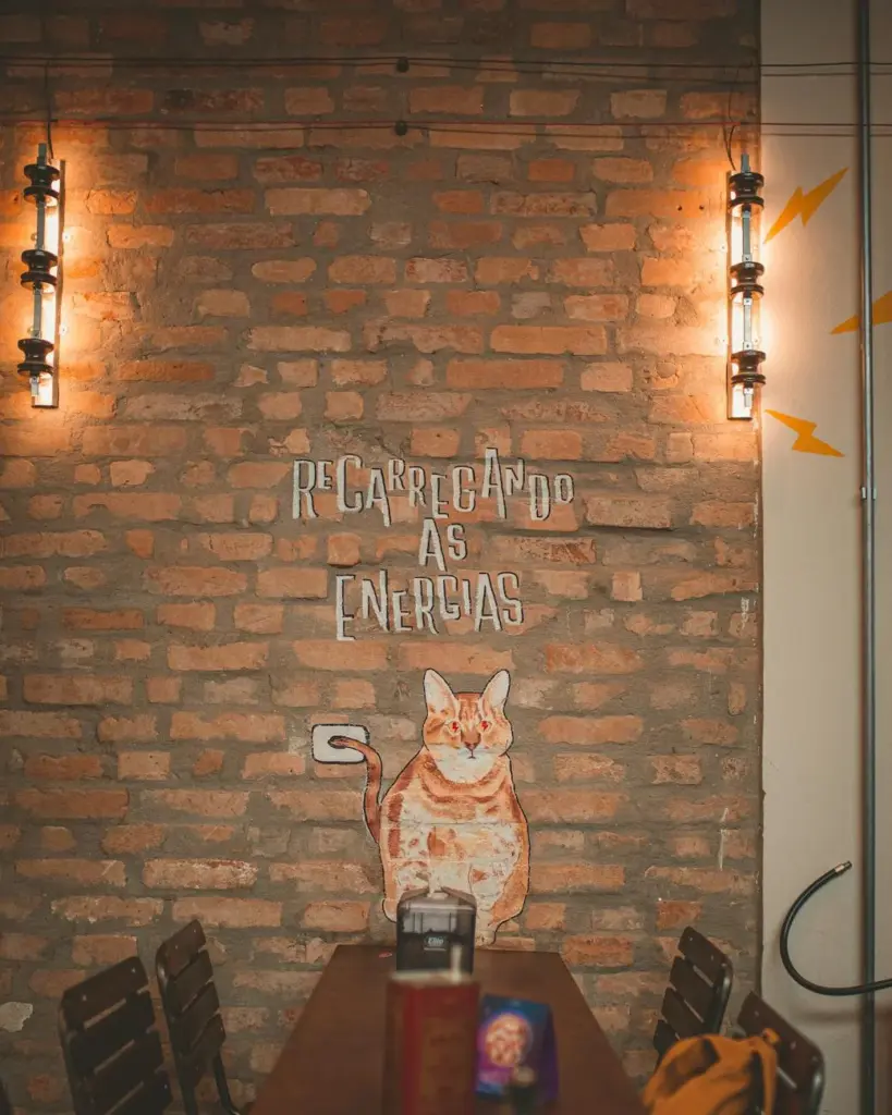 Warm brick wall with cat art and lighting in a stylish cafe interior.