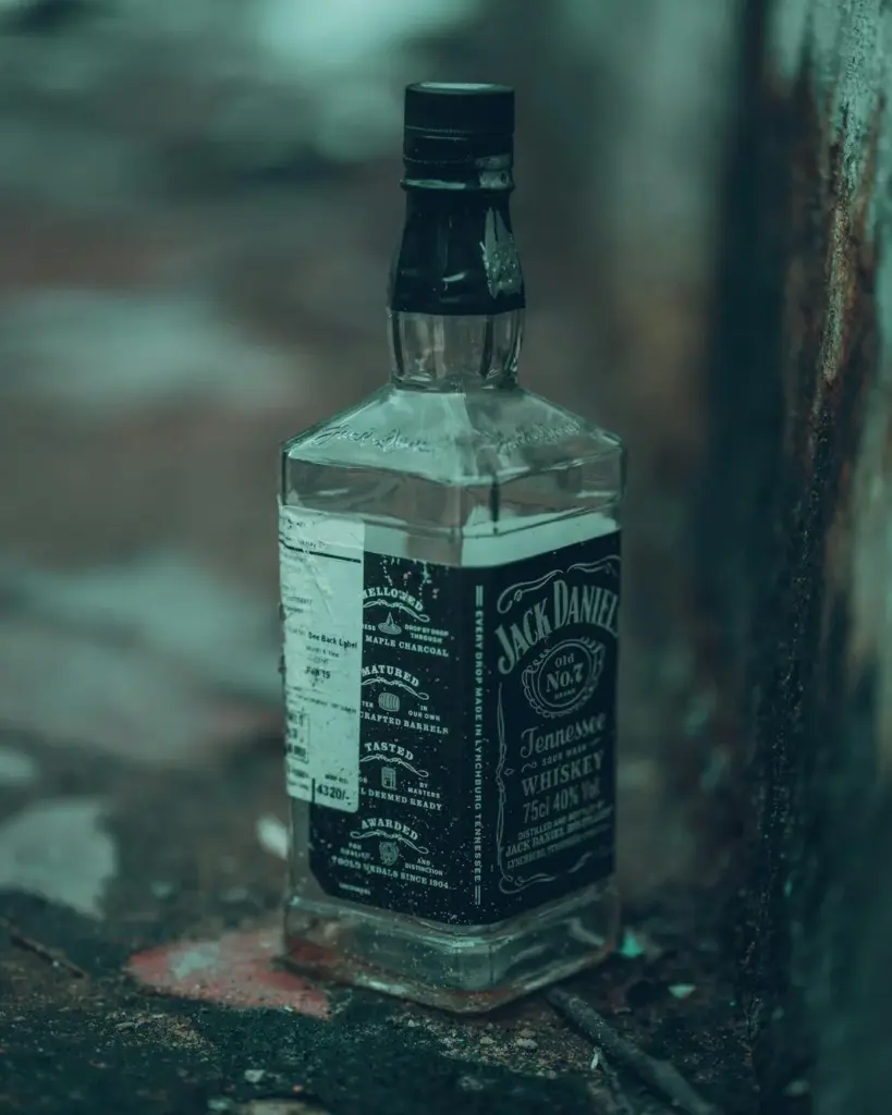 A Jack Daniel's whiskey bottle on a weathered concrete urban surface.