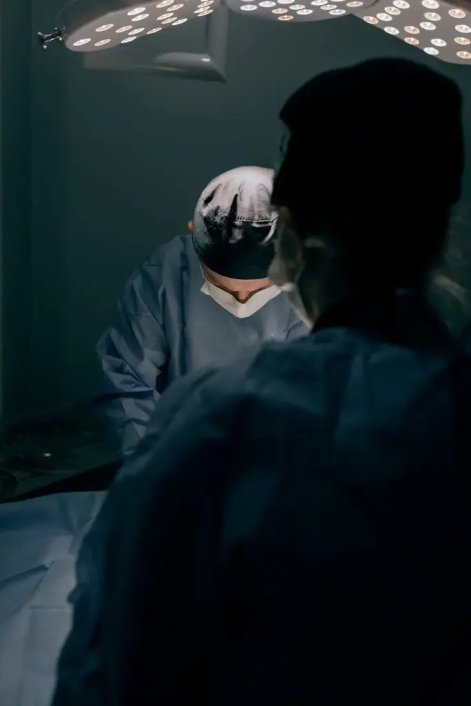 Surgeons focused on a procedure under bright surgical lights in an operating room.