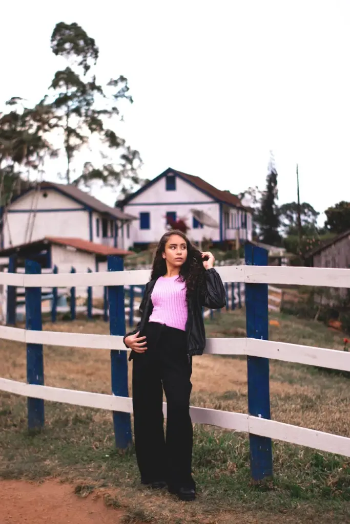 Woman leaning on a wooden fence with rustic houses in Pedra Azul, Brazil.