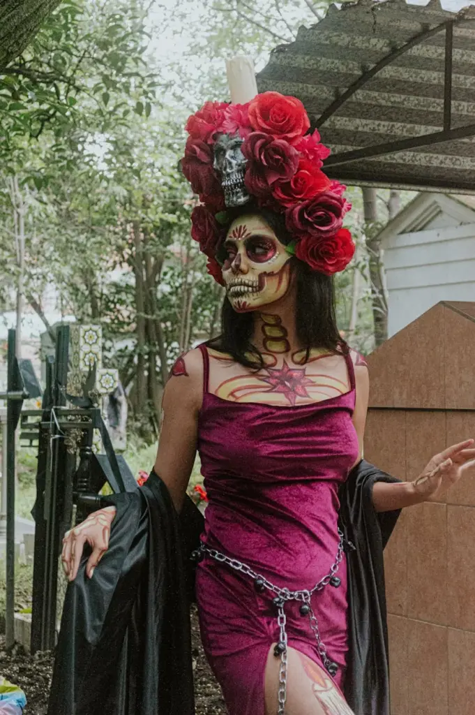 An artistic portrayal of a Catrina wearing colorful makeup and costume in a cemetery setting.