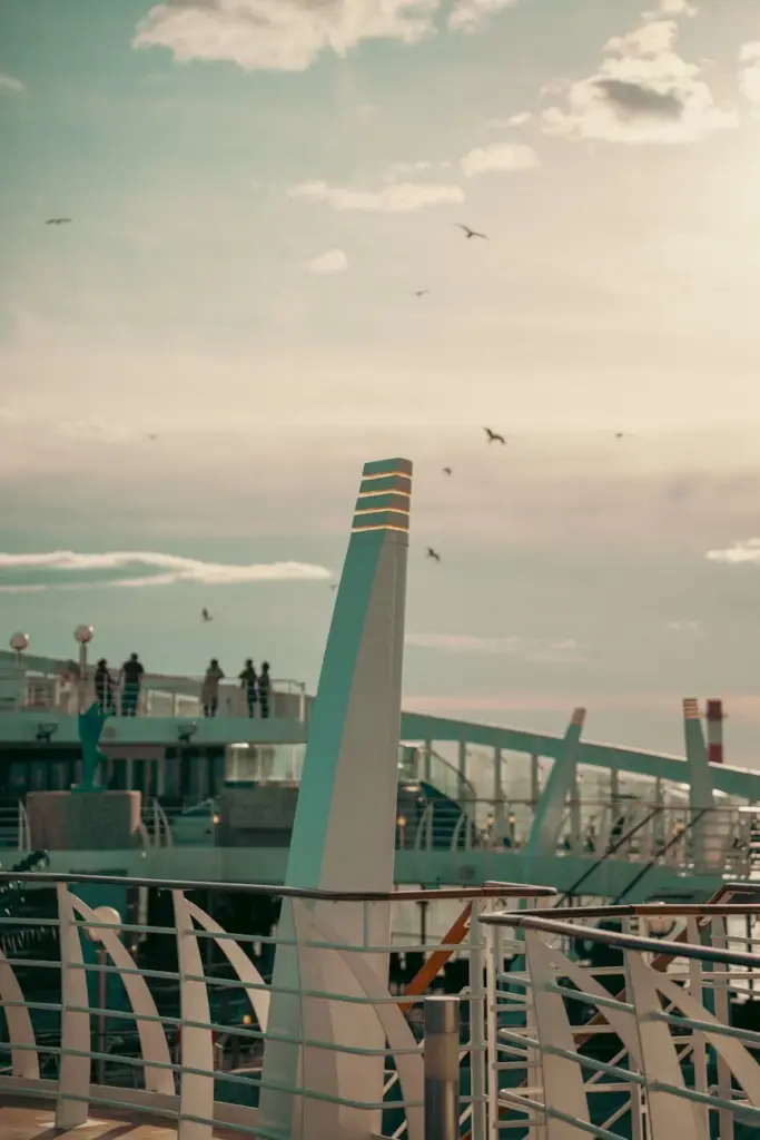 A serene morning view of a cruise ship deck with seagulls flying under a soft pastel sky.
