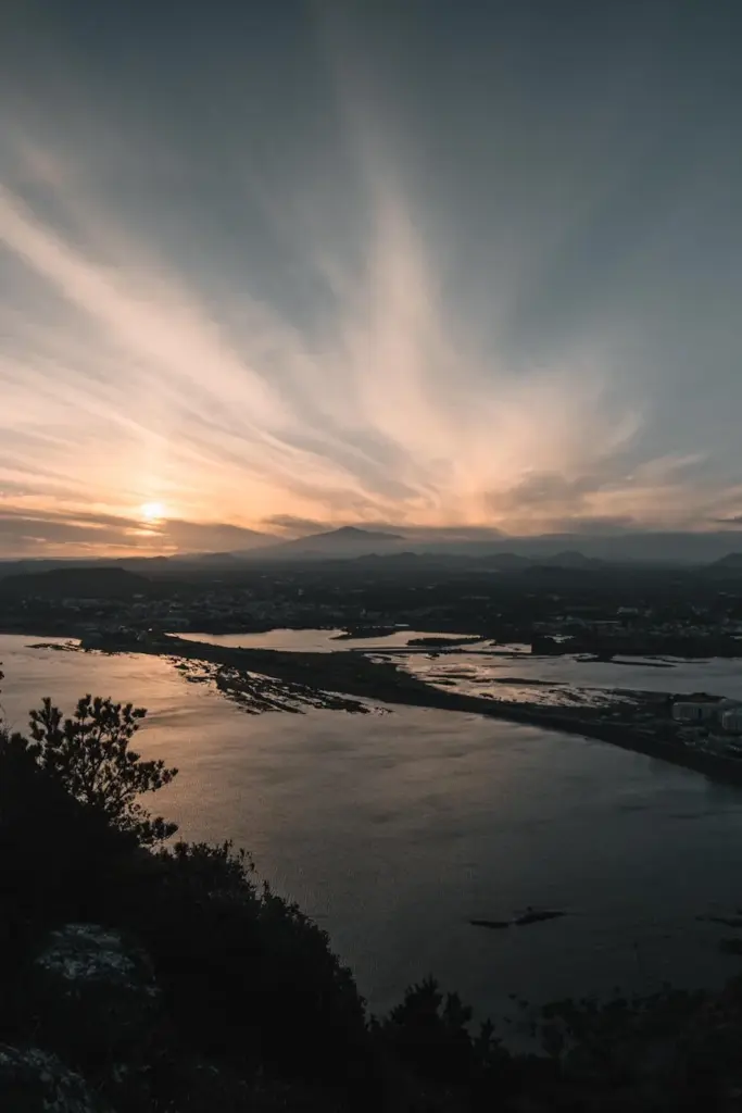 Majestic sunset view over Seogwipo coastline, Jeju, South Korea with tranquil ocean and dramatic skies.