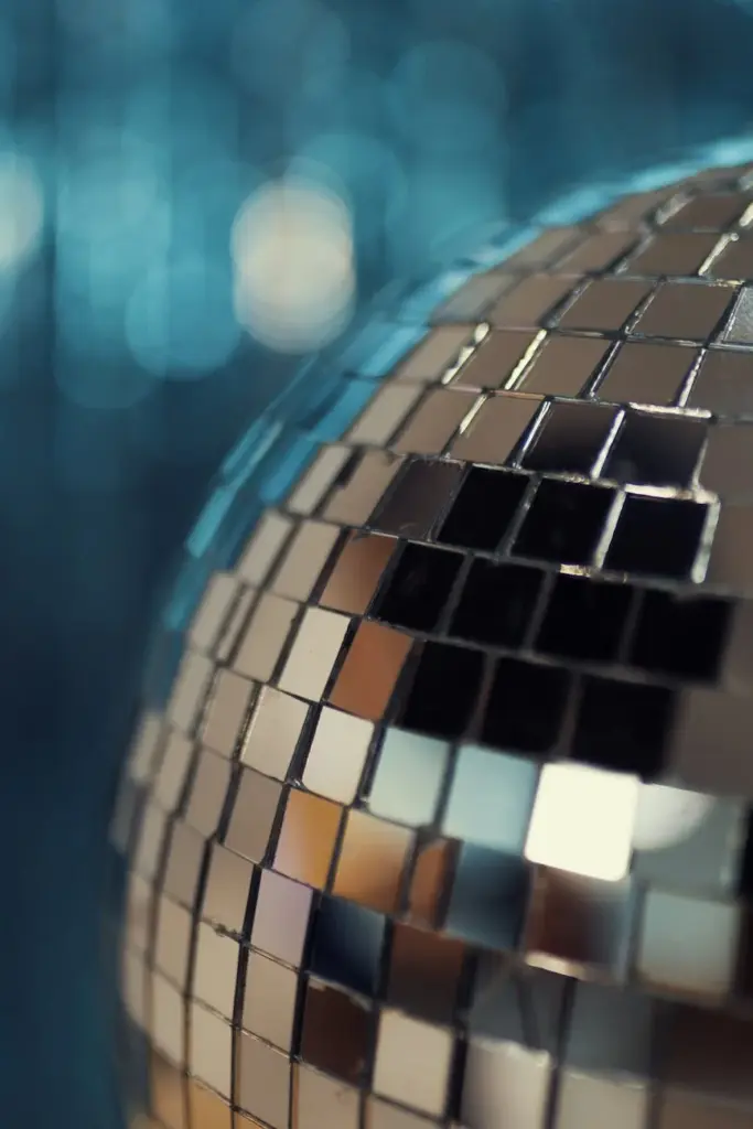 Vibrant close-up of a glistening disco ball reflecting colorful lights against a blurred background.