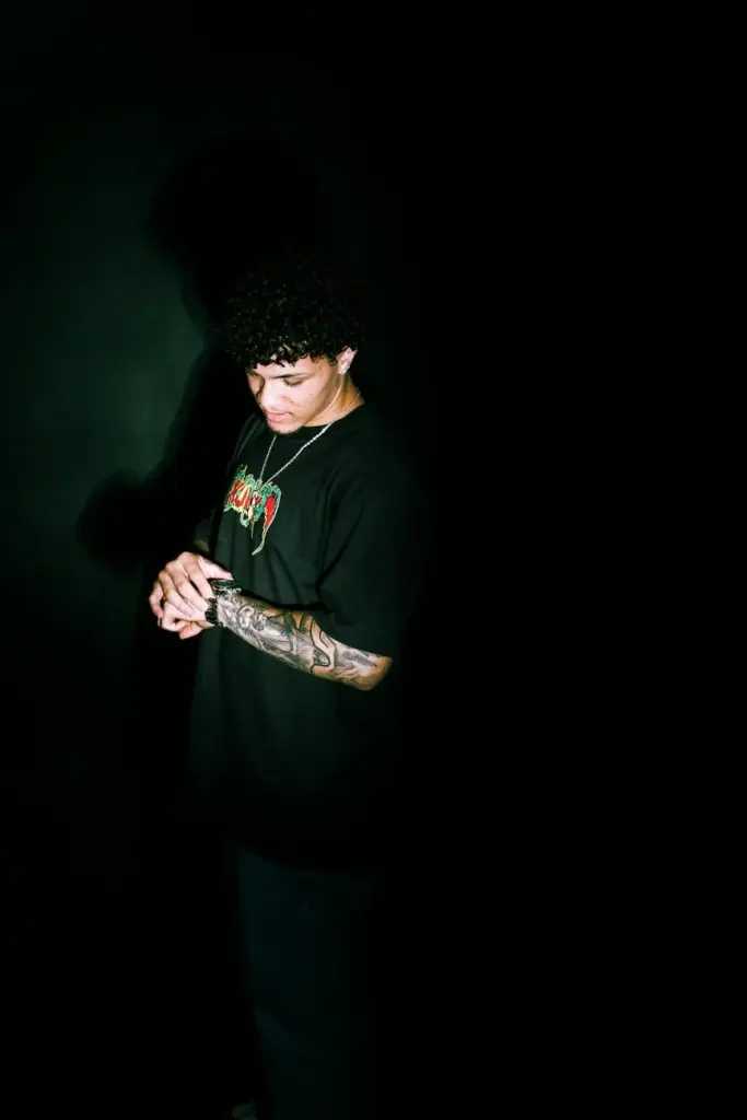 A stylish portrait of a tattooed man checking his watch in dramatic lighting.