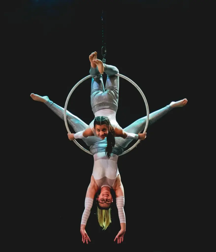 Two performers executing a breathtaking aerial dance routine with hoops on stage.
