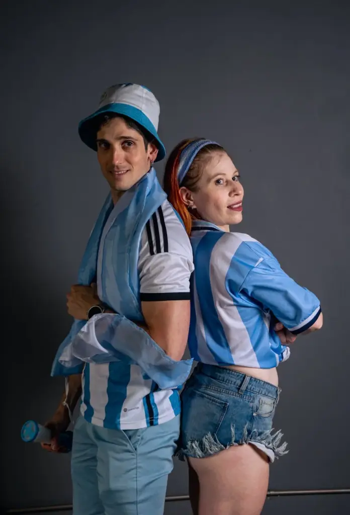 Two enthusiastic fans wearing Argentina jerseys, showcasing team spirit indoors.