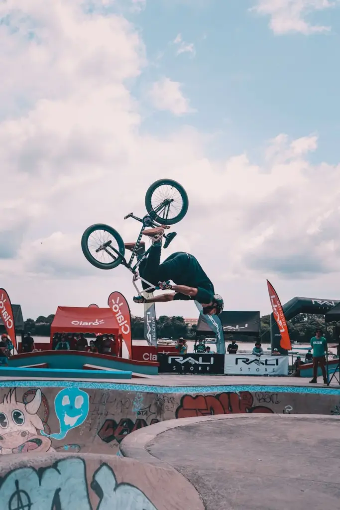 Dynamic BMX stunt performed in a vibrant skate park with colorful graffiti under a clear sky.