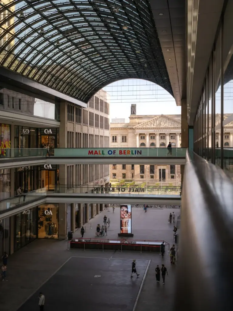 Interior view of the Mall of Berlin's modern architecture with glass ceiling and shops.