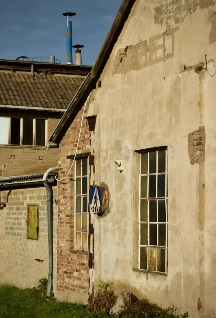 Photo of an old, weathered factory building with rustic textures and industrial pipes.