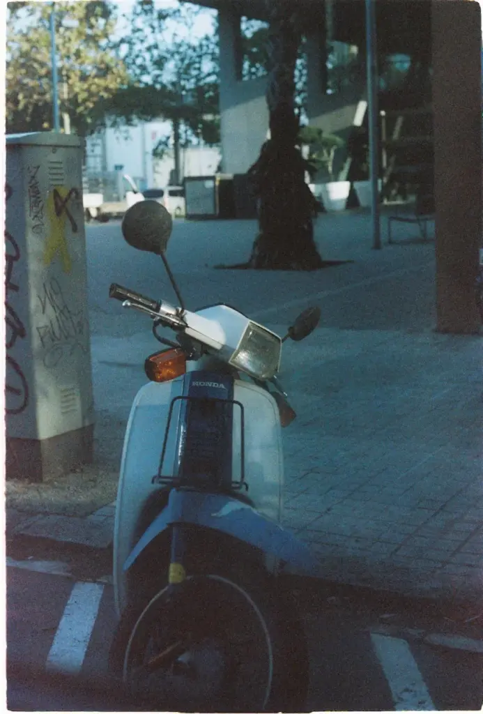 Vintage Honda Super Cub parked in sunny Barcelona street.