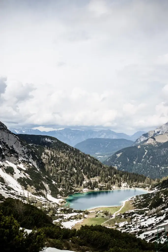 A stunning alpine lake surrounded by snowy mountains and evergreen trees, captured on a winter day.
