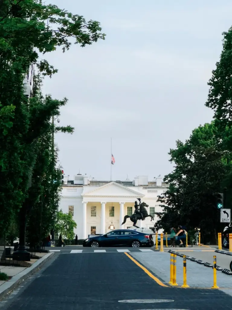 Photograph of the White House from Lafayette Square, showcasing historic architecture and vibrant greenery.
