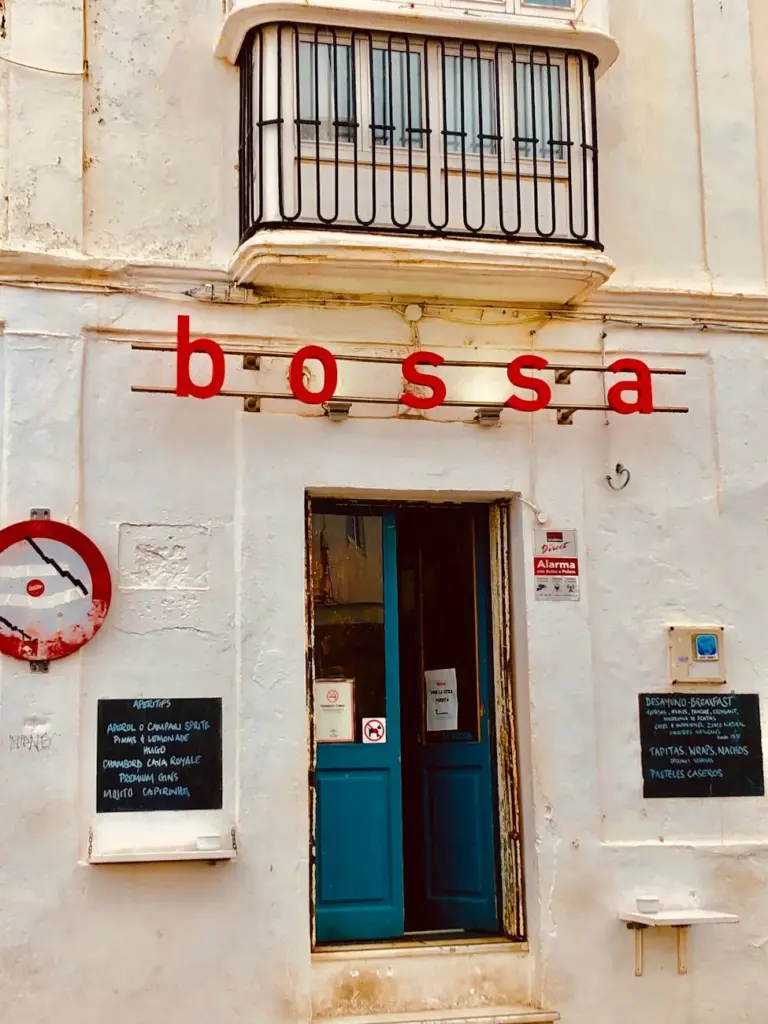 Stylish cafe entrance in Tarifa, Spain, featuring a blue doorway and balcony.