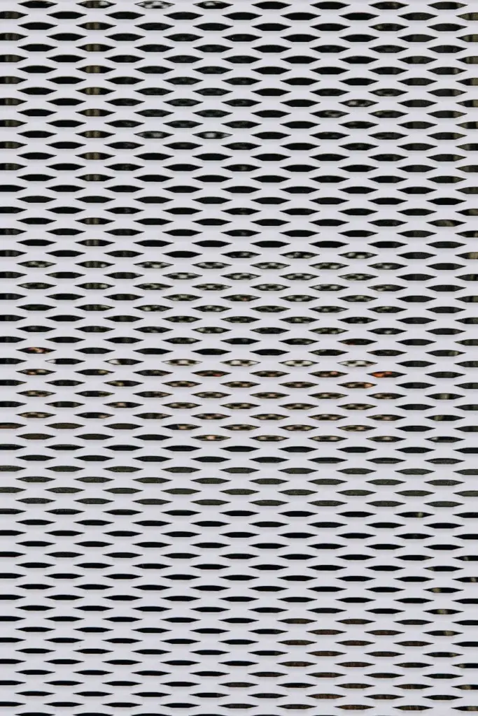 Close-up of a textured metal grid facade with repeating geometric patterns.