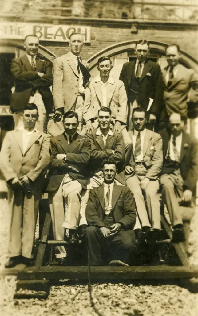 A sepia-toned group photograph of men in formal attire from a bygone era, showcasing vintage style.