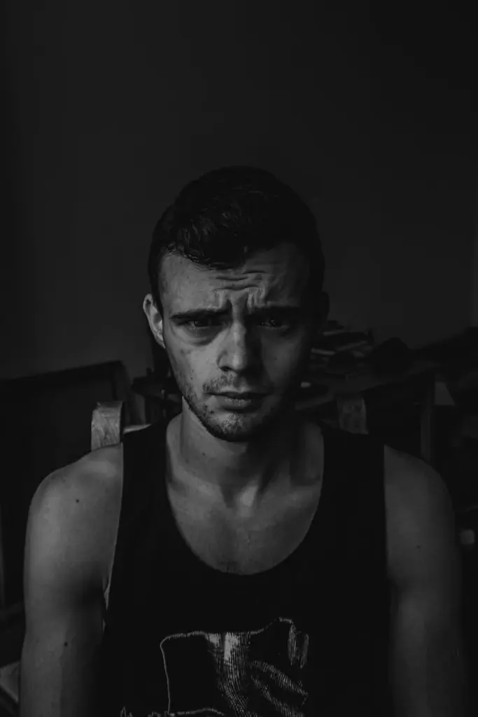 Striking black and white portrait of a young man with intense expression, captured indoors.