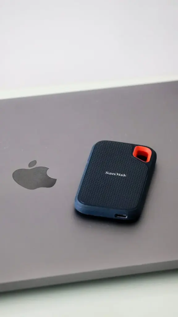 Close-up of a portable SanDisk external hard drive resting on a laptop surface, highlighting modern data storage solutions.