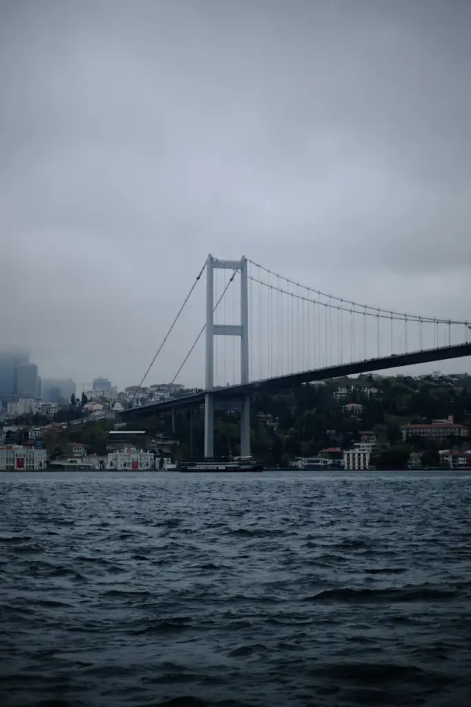 A misty morning view of the Bosphorus Bridge spanning over the water in Istanbul.