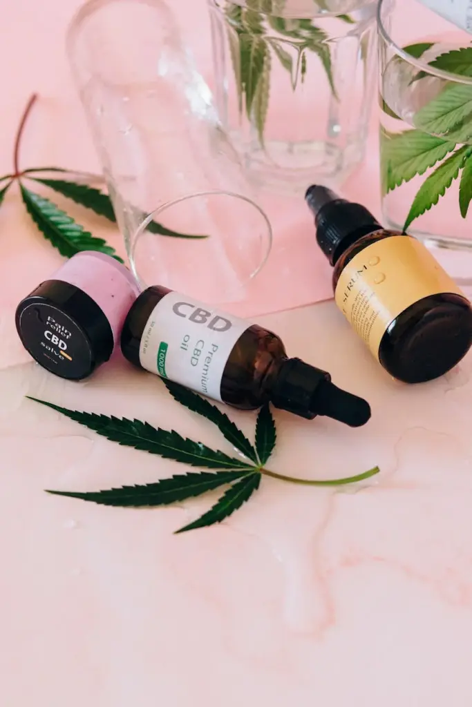 Aesthetic arrangement of CBD oil bottles with cannabis leaves on a pink background.