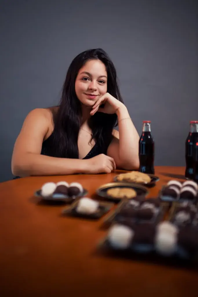 A woman in Brazil with desserts and sodas, celebrating indoors.