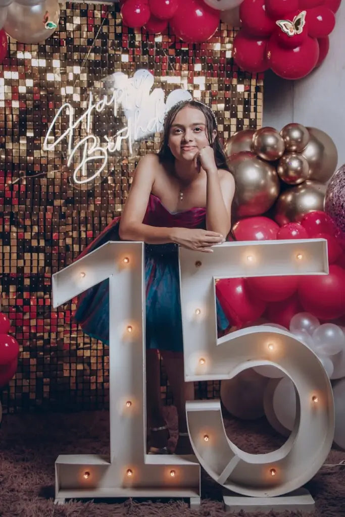 Smiling girl enjoying her 15th birthday celebration with balloons and lights.