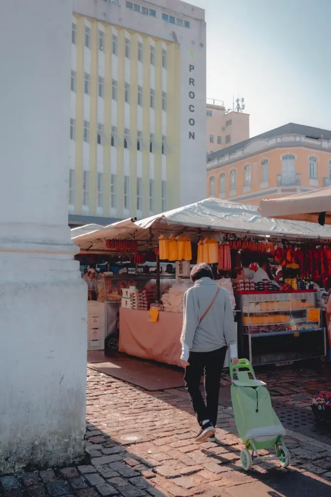A vibrant street market in Florianópolis, Brazil, featuring a variety of stalls and a pedestrian with a shopping cart.