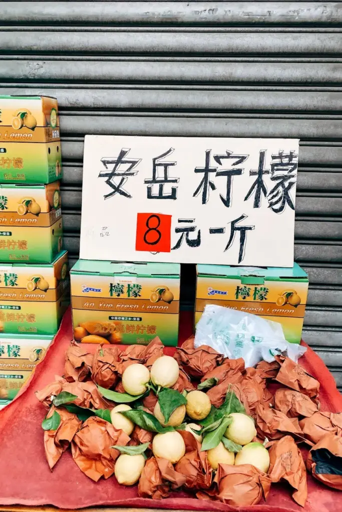 Fresh lemons displayed at a Chengdu market stall with signage in Chinese text.