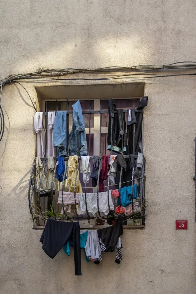 Colorful laundry drying on barred window of an apartment building.