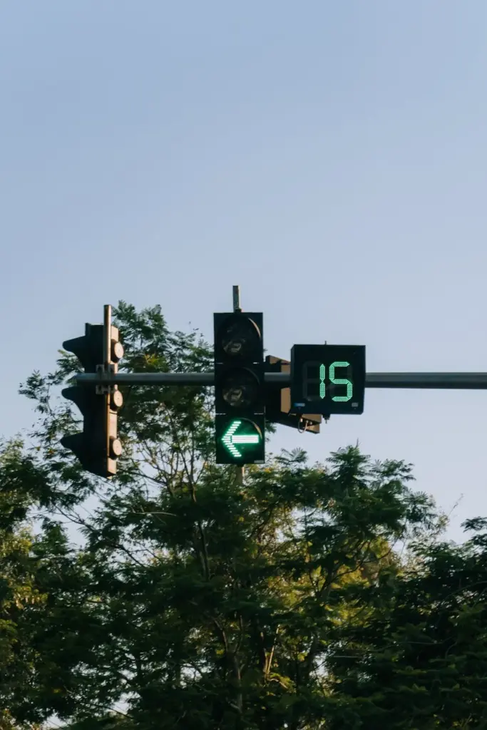 Traffic light with a digital countdown timer amidst greenery in Hanoi, Vietnam.