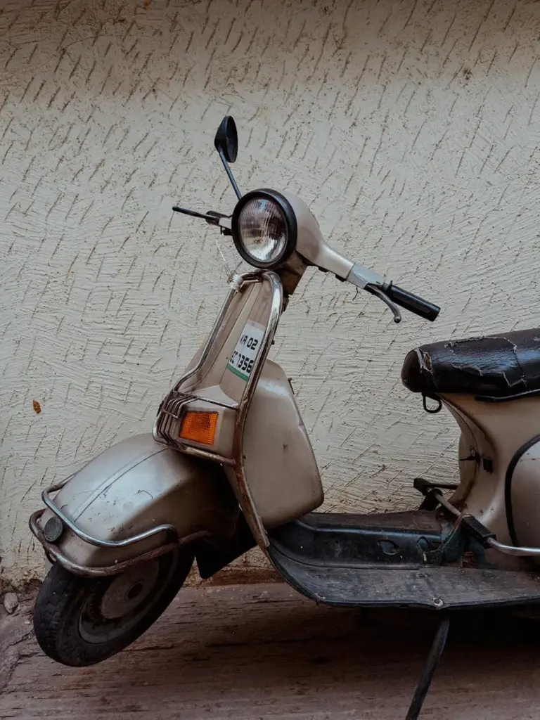 A classic scooter parked next to a concrete wall, evoking a retro vibe.