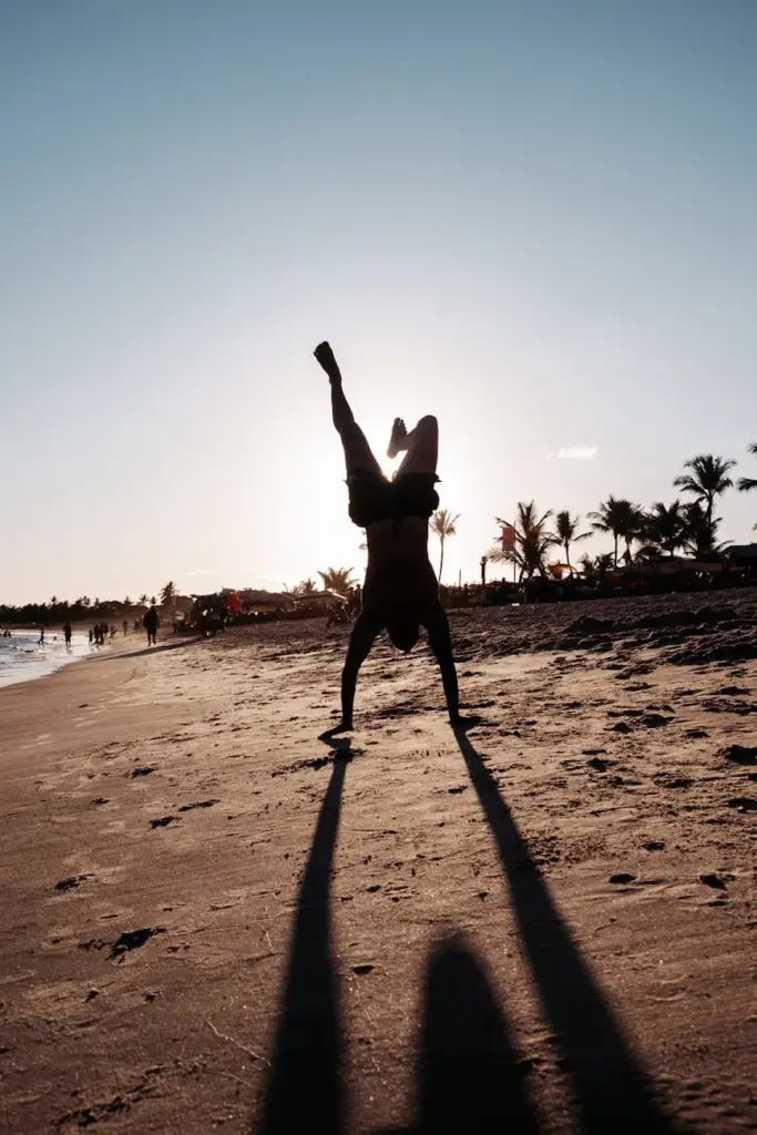 A silhouette of a man doing a handstand on the beach during sunset in Porto Seguro, Brazil.