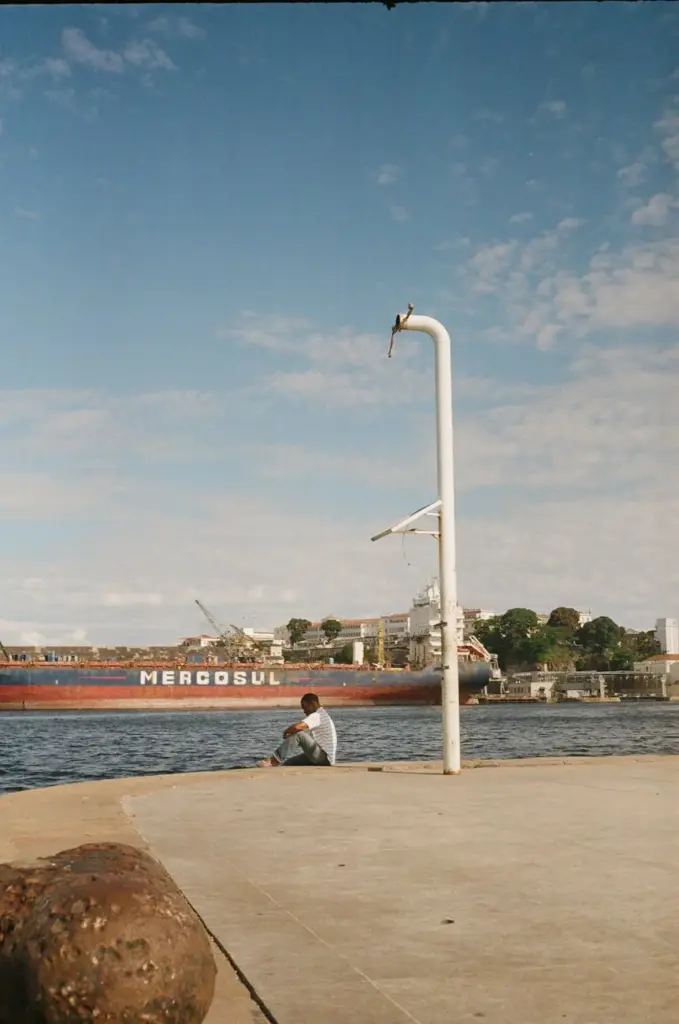 A man enjoys a peaceful moment by the waterfront with a view of a ship in Rio de Janeiro, Brazil.