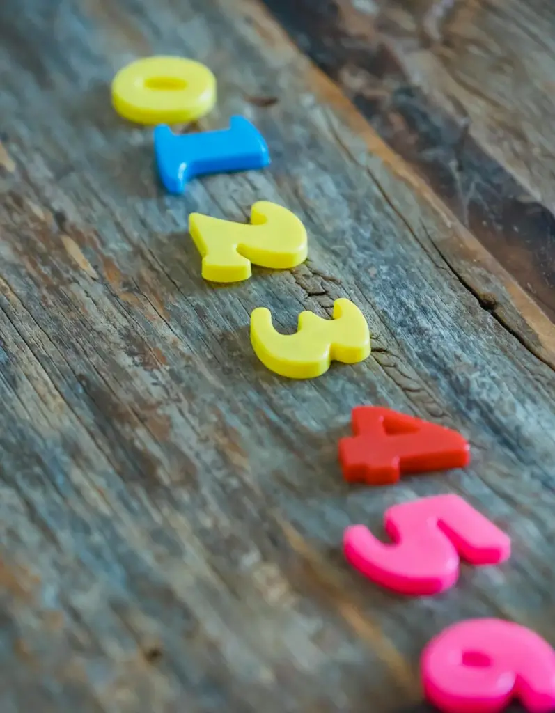Bright plastic numbers arranged on rustic wood background for educational concept.
