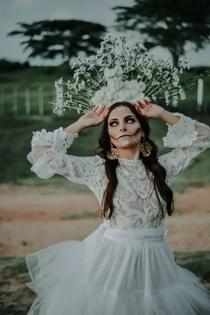 Beautiful Catrina in a lace dress with floral headdress, celebrating Día de Muertos outdoors.