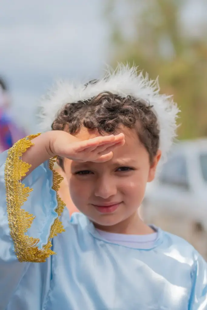 Young child in an angel costume enjoying a sunny outdoor festival in Brazil.