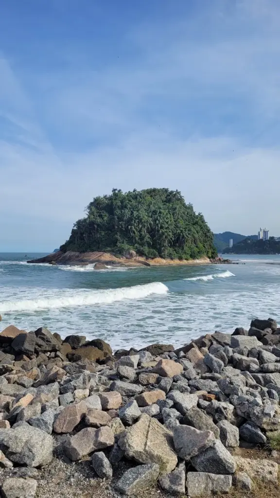 A serene view of an island surrounded by waves and a rocky beach, perfect for travel inspiration.