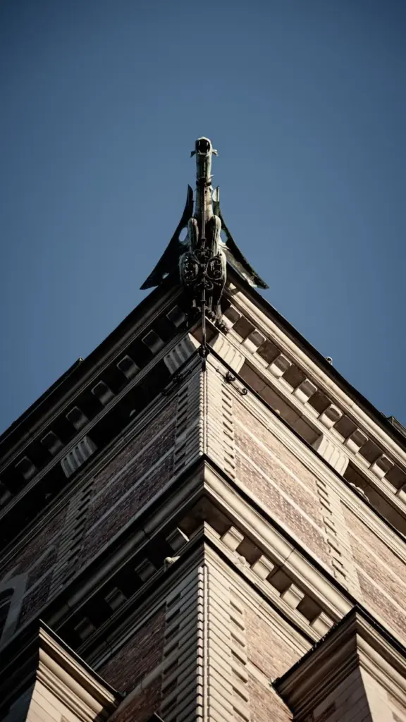 Detailed view of a Stockholm building spire against a clear blue sky, showcasing intricate design.
