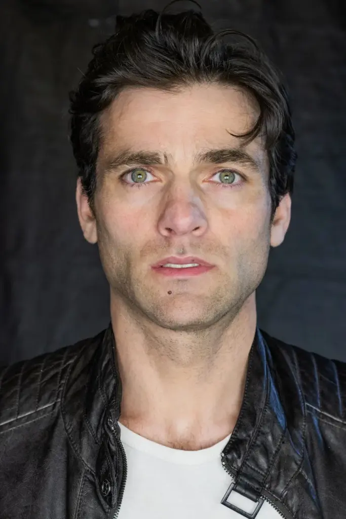 Close-up portrait of a man wearing a leather jacket with a neutral expression.
