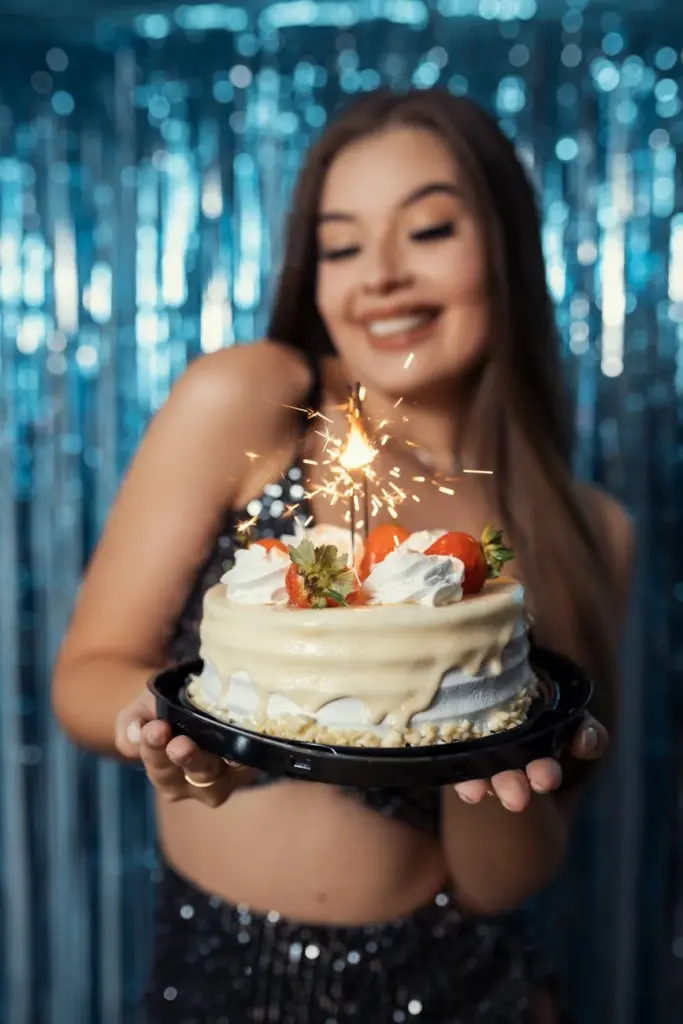 Woman holding a sparkling birthday cake with strawberries at a celebration in Brazil.