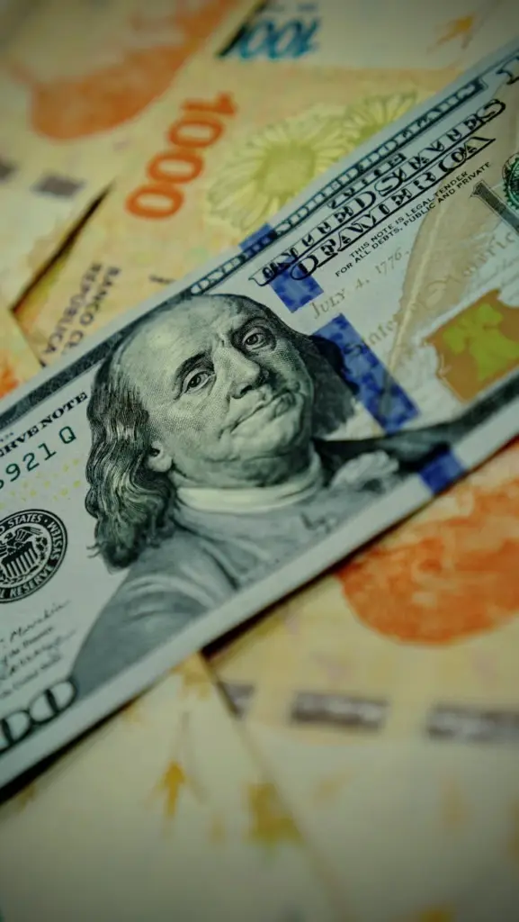 Detailed image of U.S. dollar and Argentine pesos banknotes highlighting currency exchange.