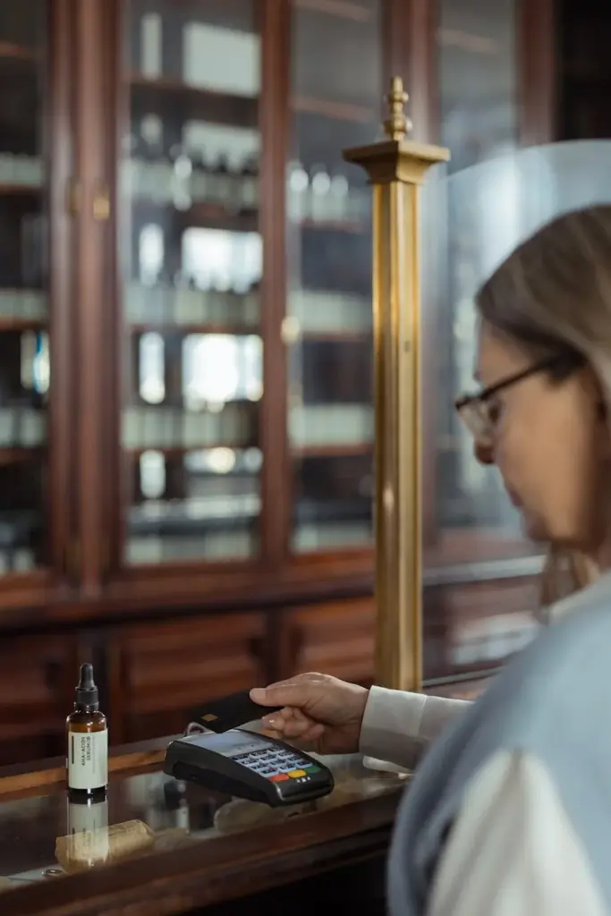 A woman uses a payment terminal indoors with vintage shelves in the background, illustrating a modern transaction.