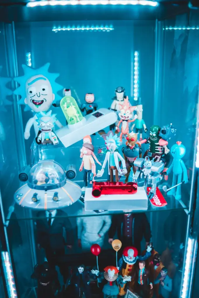 High angle of glass cupboard with collection of assorted figures of different cartoon characters under LED light