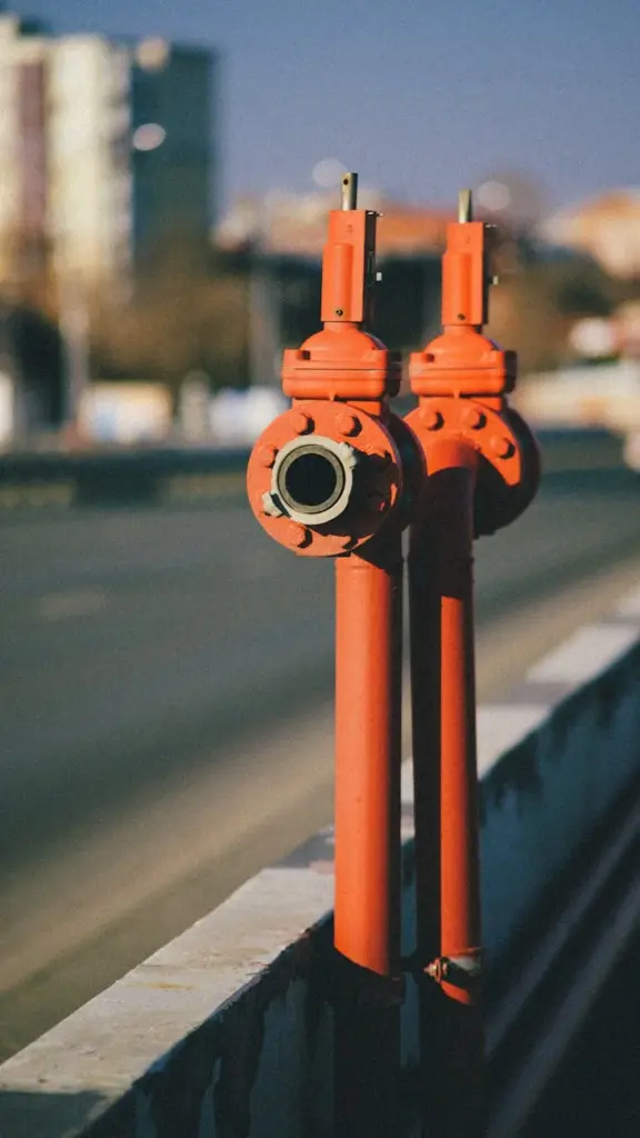 Red industrial pipes along an urban street under a clear sky. Ideal for cityscape and industrial themes.