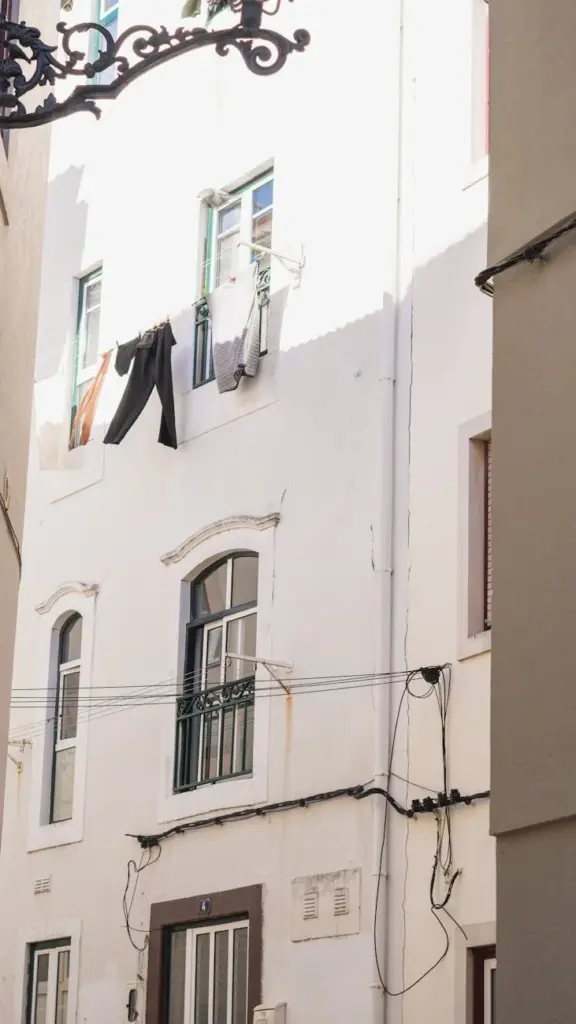 Bright white facade of a narrow European street with drying clothes.