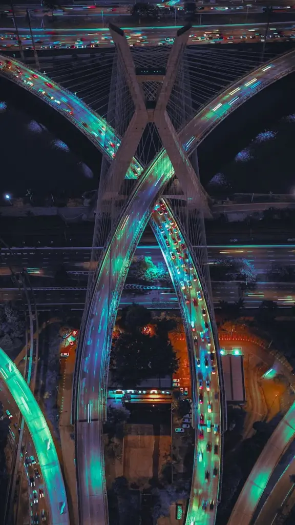 Stunning aerial shot of a brightly lit modern bridge at night, showcasing urban architecture.